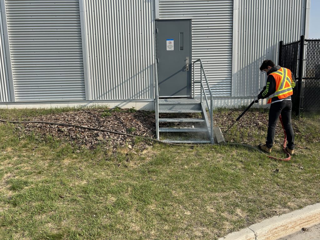 A man in an orange vest is using a power washer.